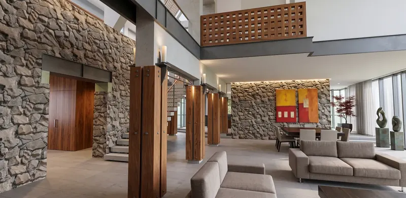 Colonnade of wooden columns with iron candle holders and arch tracery, between stone walls and the living area