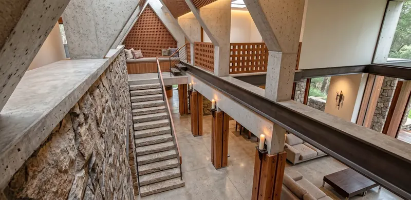 View down into the Sunlit Atrium House atrium: concrete ribs, stone stair to the window seat, colonnade below