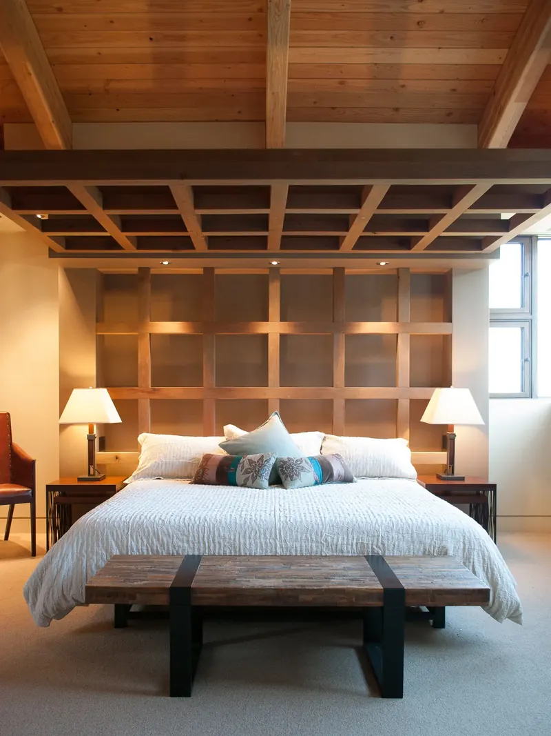 Bed beneath a coffered timber canopy with a steel-and-wood bench at its foot
