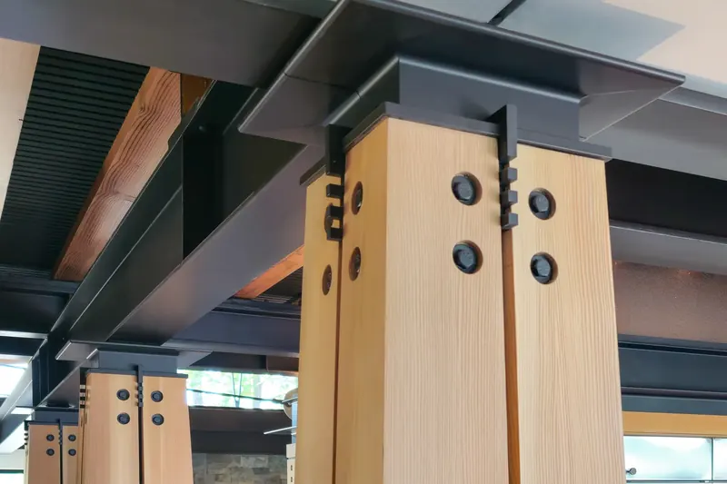 Timber column with bolted steel connections meeting an exposed steel beam
