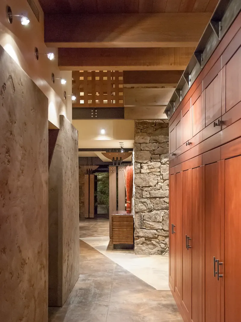 Entry hall with plaster walls, a stone pier and a row of red-stained cabinets