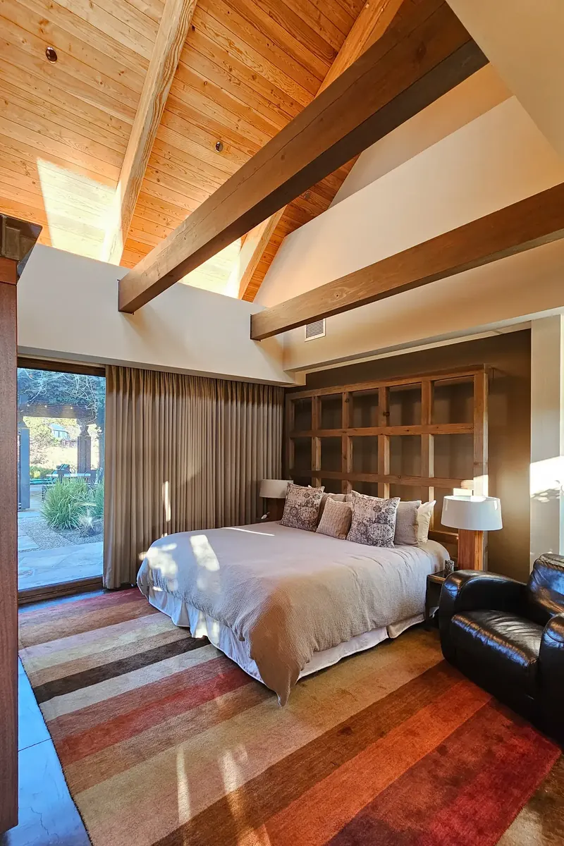 Guest bedroom with a vaulted wood ceiling, timber beam and striped rug