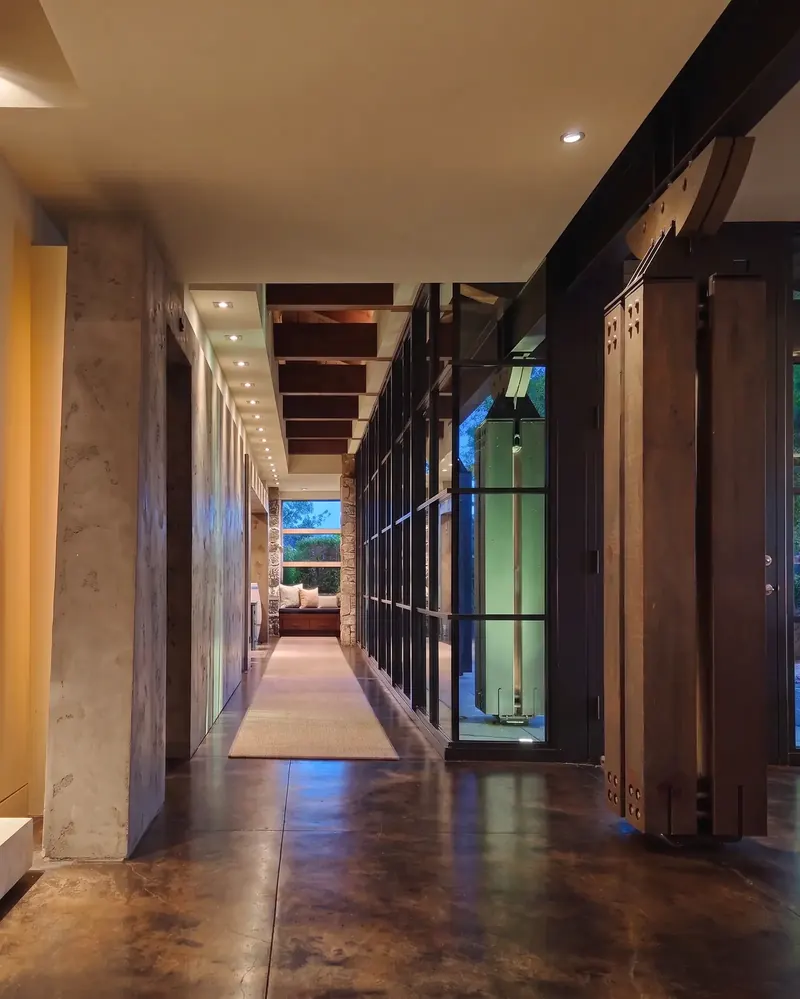 Gallery hallway at dusk with warm light on plaster walls and timber posts