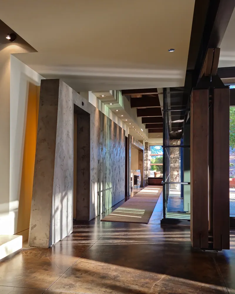 Long gallery hallway with plaster walls, timber posts and concrete floors in sunlight