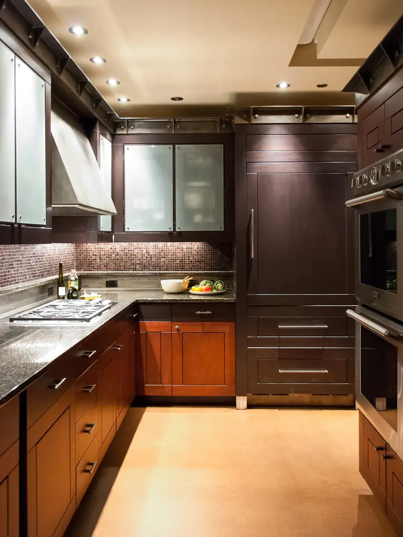 Kitchen cooking area with a range hood, built-in ovens and dark cabinetry