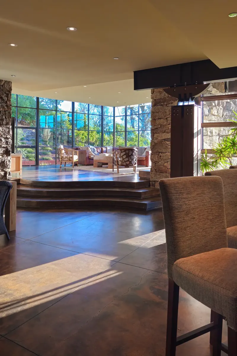 View from a kitchen stool across concrete floors and steps up to the glass living room