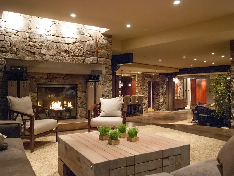 Living room at night with fire burning and the kitchen glowing beyond