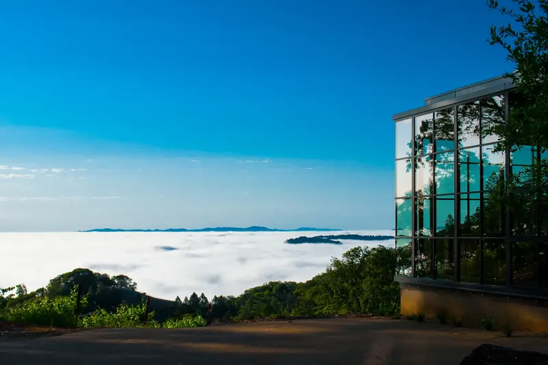 Corner of the glass living room beside a valley blanketed in morning fog