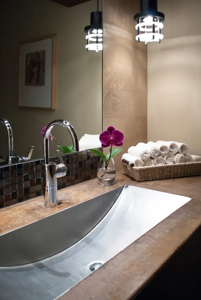 Powder room with a steel trough sink, tile backsplash and pendant lights