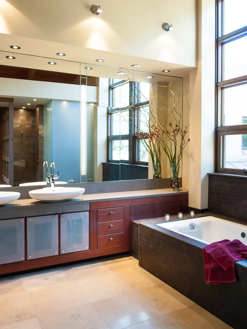 Bathroom with double vessel sinks, tiled soaking tub and a tall window