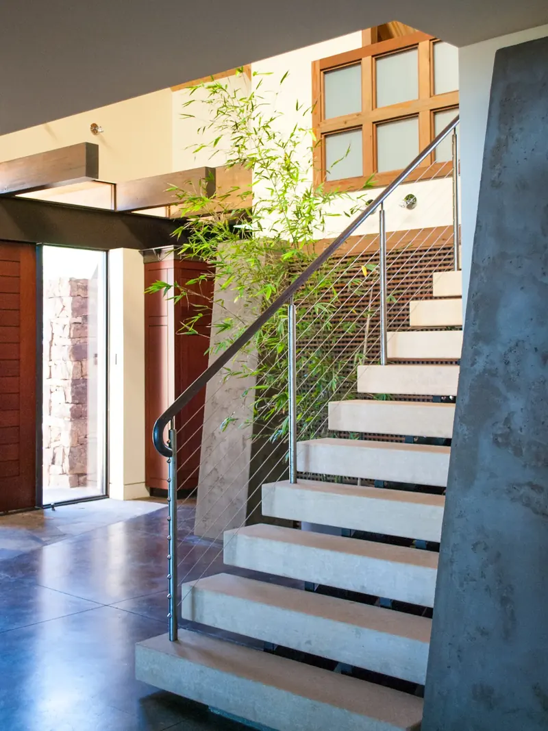 Floating stone treads with a steel cable rail rising beside the front door