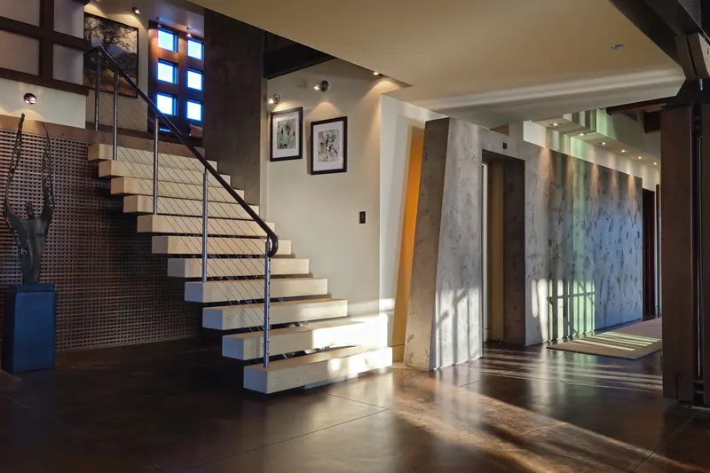 Stair hall with floating stone treads, framed art and a plaster column in daylight