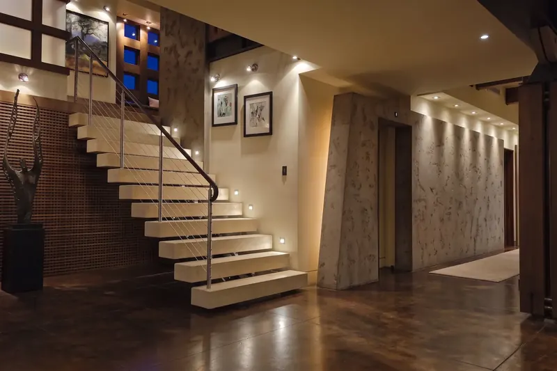 Floating stone stair lit by step lights in the evening stair hall