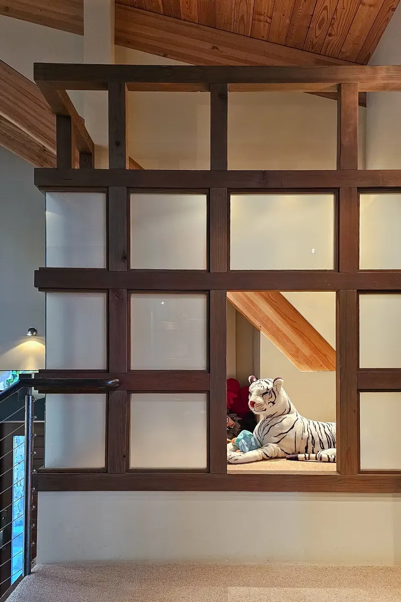 Timber and frosted-glass grid opening into a loft play space with a toy tiger