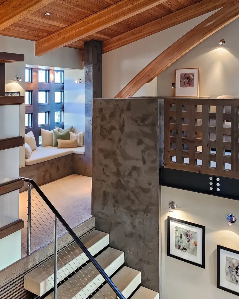 Upper stair landing with a cushioned window seat beneath a timber ceiling