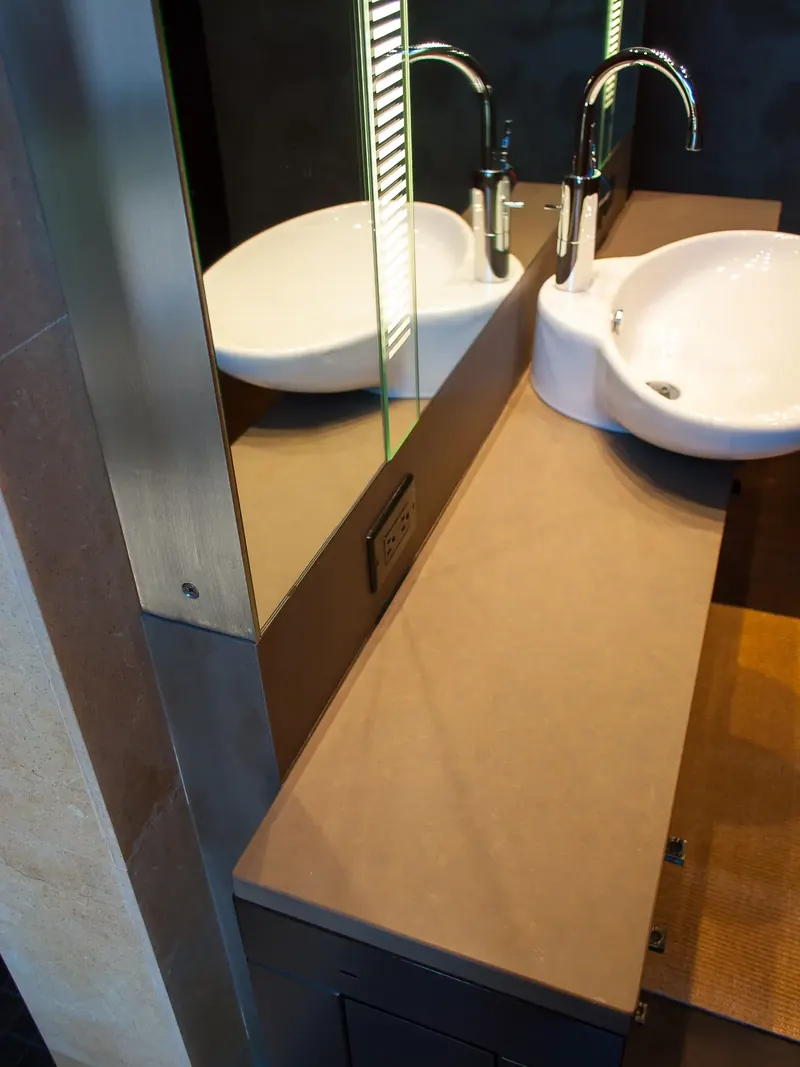 Stone vanity top with white vessel sinks and a mirror reflection