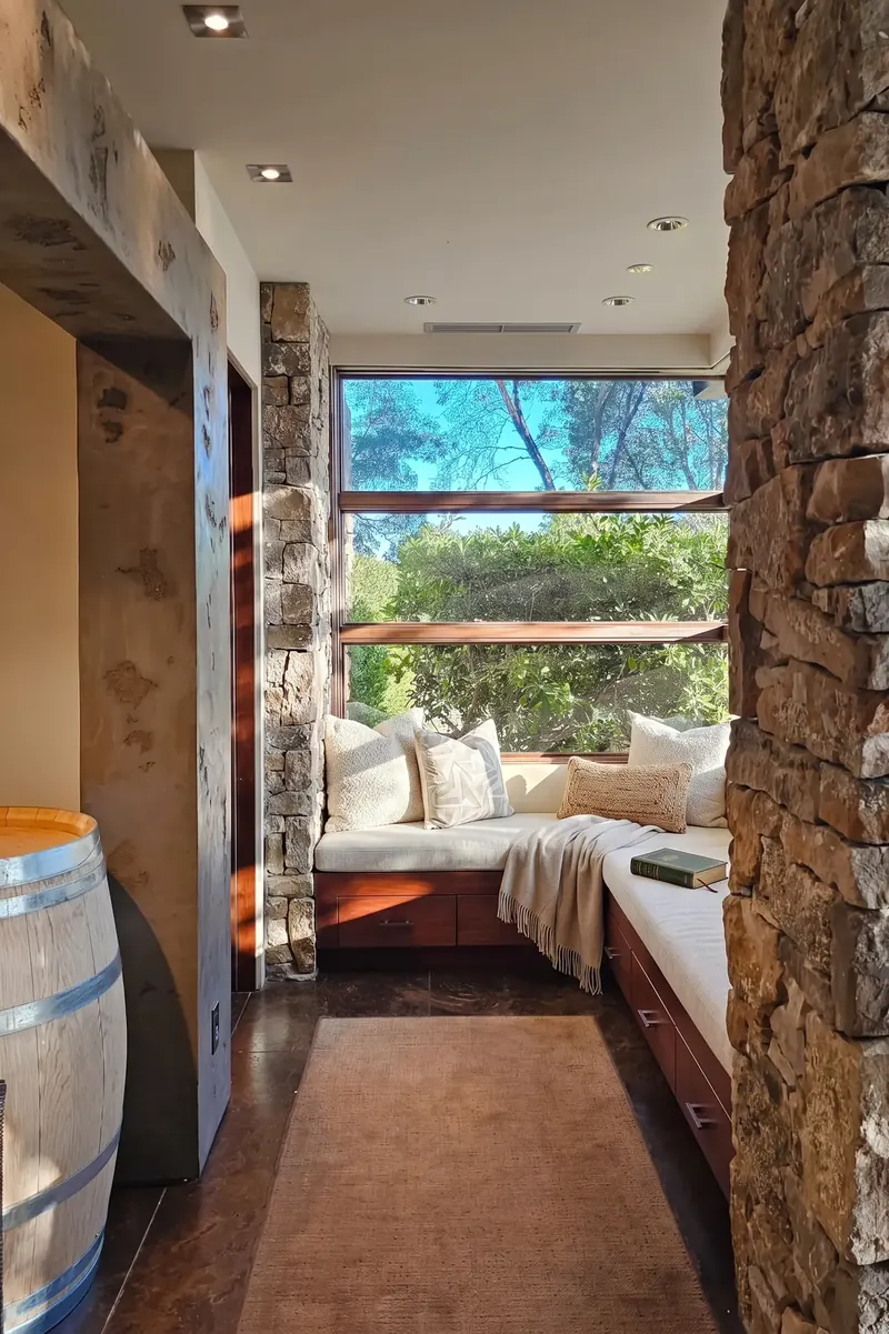Window seat nook beside a stone wall, with a wine barrel by the entrance