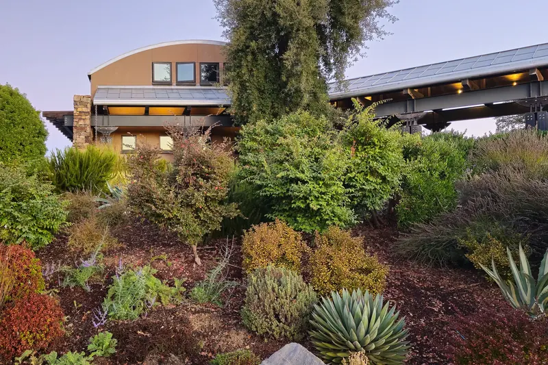 Long covered walkway leading to the barrel-roofed winery above a planted slope