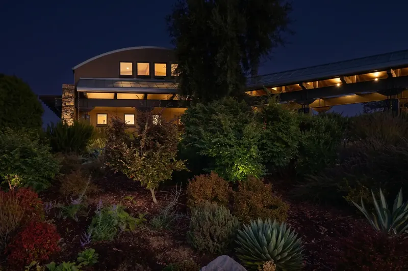 Winery and covered walkway glowing at night above the garden