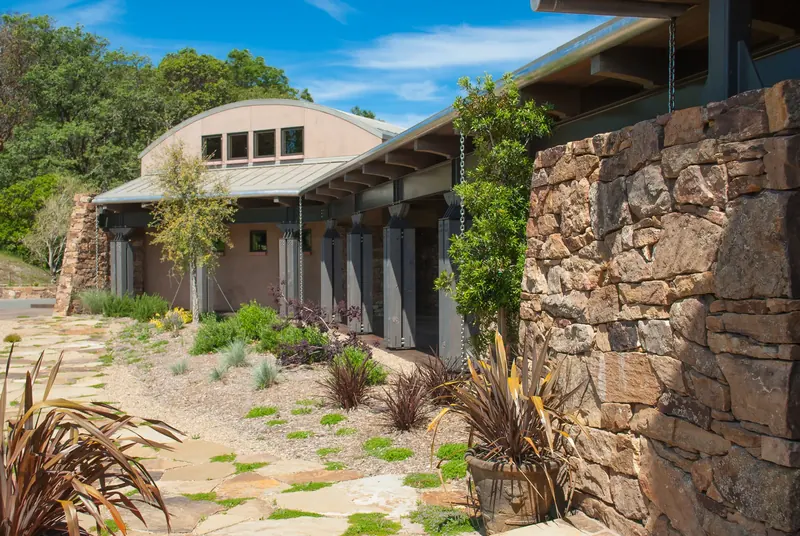 Covered walkway along a stone wall toward the winery building