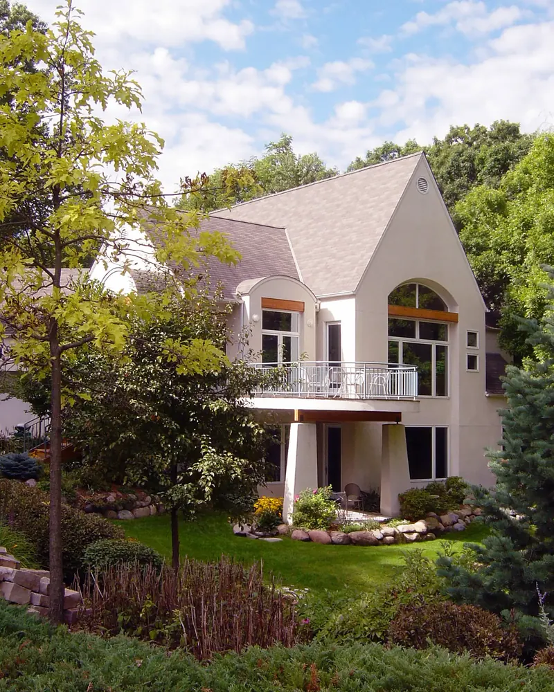 White stucco gable house with arched windows and a balcony above a landscaped garden, Washington