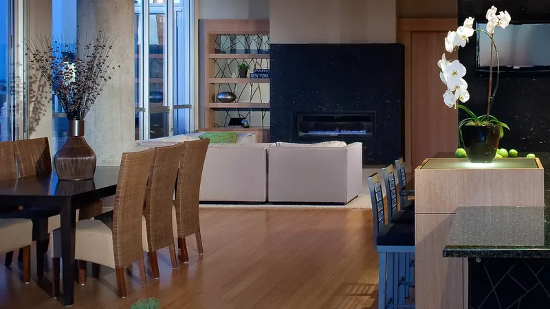 Open loft with dining table, white sofas and black stone fireplace, an orchid on the kitchen island