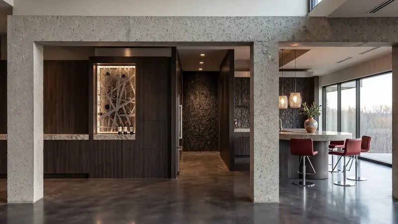 Concrete-framed openings to a lit wine rack behind a metal grille and a curved bar with red stools, Boston