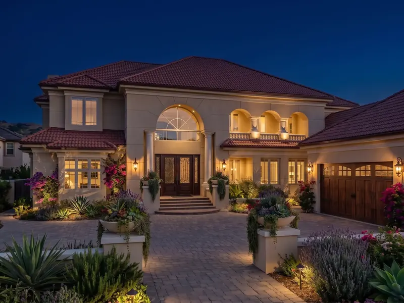 Villa at night, arched windows and loggia glowing above the landscaped motor court