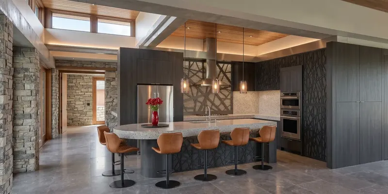 Kitchen with a long rounded island, leather stools, stone walls and patterned cut-out screens, Miami