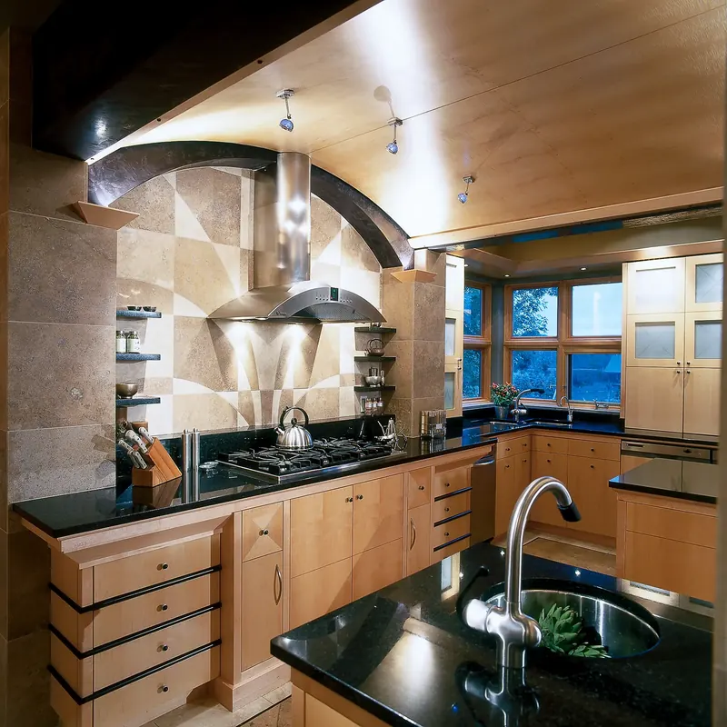 Cooktop wall with stainless hood and geometric stone backsplash under a curved beam