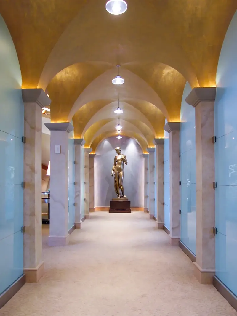 Gallery hall with gold groin vaults, frosted glass panels and a bronze statue at the end, Naples