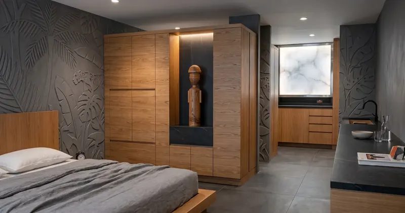 Condo bedroom with leaf-relief gray walls and a wood wardrobe with a lit niche holding a carving